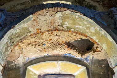 Kadim bir binada, kırmızı tuğladan bir mezar şeklinde bir tavan. Eski tavanda bir delik.