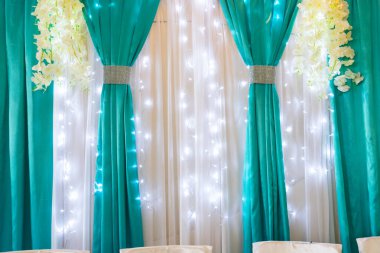 Şölen salonunun dekorasyonu beyaz ve turkuaz kumaşla süslenmiş..