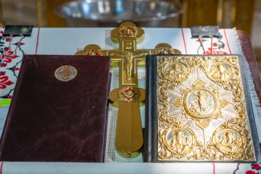 Two Bibles and a large golden cross on an altar in a Christian church.