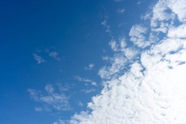 Mavi gökyüzünün arka planında beyaz kümülüs bulutları.