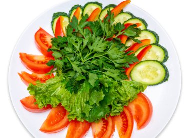 Sliced tomatoes, cucumbers, red pepper and garnished with parsley and lettuce. Fresh Vegetables Plate. Isolate