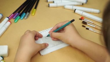 The girl writes letters with a pencil under the stencil. Back to school