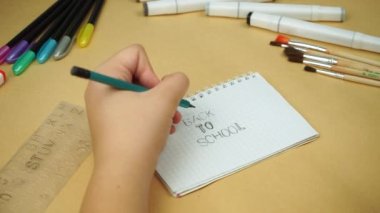A teenager draws with his left hand on the inscription Back to school