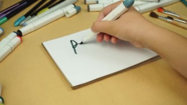 A girl writes words back to school with a marker in a notebook
