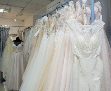 White and cream wedding dresses on a hanger in a bridal boutique.