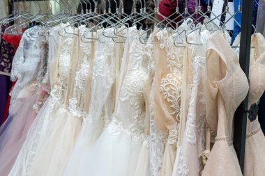 White and cream wedding dresses on a hanger in a bridal boutique. Close up.