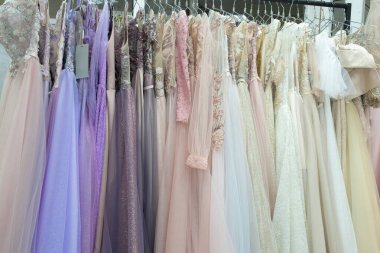 Many different evening and wedding dresses close-up on a hanger in a store.