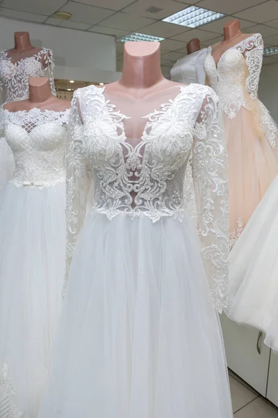 A beautiful white wedding dress on a mannequin. A close-up of a dress against other wedding dresses in a bridal shop.