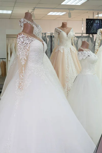 A beautiful white wedding dress on a mannequin. A wedding dress on the background of other wedding dresses in a wedding salon