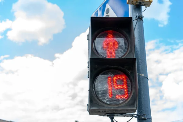 Red traffic light for pedestrians on the background of the blue sky. Red number 19 at the traffic light. Place for writing, copy space.