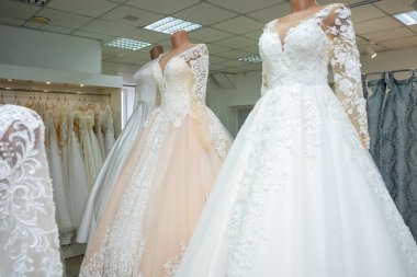 Beautiful wedding dresses in a bridal boutique on mannequins.