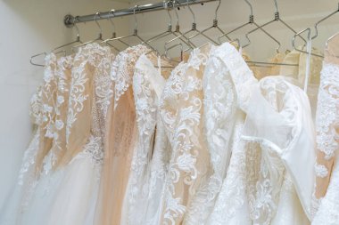 White and cream wedding dresses on a hanger in a bridal boutique. Close up.