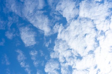 Mavi gökyüzünün arka planında beyaz kümülüs bulutları.