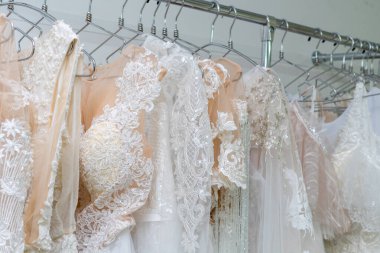 White and cream wedding dresses on a hanger in a bridal boutique. Close up.