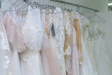 White and cream wedding dresses on a hanger in a bridal boutique. Close up.