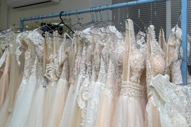 White and cream wedding dresses on a hanger in a bridal boutique. Close up.