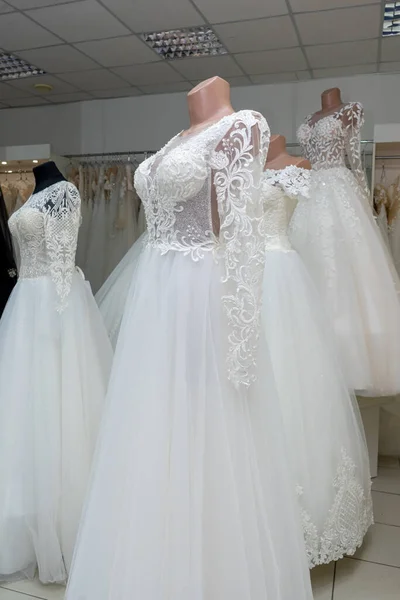 A beautiful white wedding dress on a mannequin. A close-up of a dress against other wedding dresses in a bridal shop.