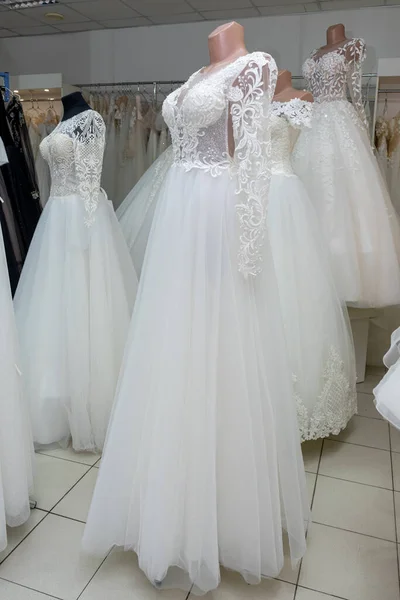 A beautiful white wedding dress on a mannequin. A close-up of a dress against other wedding dresses in a bridal shop.