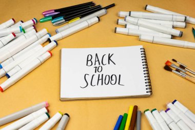 School background. A variety of school supplies and a notebook in the center with the inscription back to school.
