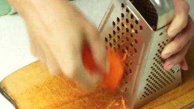 A female cook grates carrots. Grinding carrots on a grater close-up.