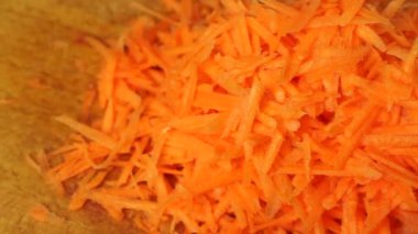 Grated juicy carrots on a wooden kitchen board close-up.