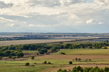 Madrid, İspanya; 09-25-2021: Pistlerden birinin, terminallerden birinin ve yakınlardaki tarlaları Madrid Barajas havaalanındaki kontrol kulesinin görüntüsü