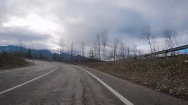 Güzel bir kış gününde dağların arasında alçak bulutlu köyler arasında El Bierzo 'da bir dağ yolunda giden hızlı bir kamera görüntüsü.