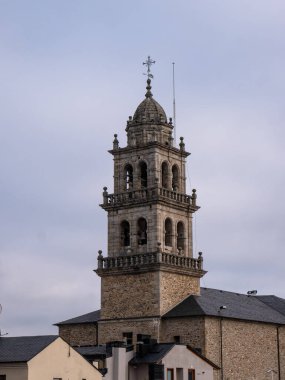 Ponferrada, Leon, İspanya; 12-12-2021; Basilica de la Encina de Ponferrada 'nın çan kulesi, çanları, kubbeyi ve tepesindeki haçı gösteren binalar arasında yer alıyor.