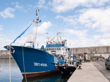 Laredo, Cantabria, İspanya; 08-17-2021: Mavi balıkçı teknesi Laredo balıkçılık limanına yanaştı ve balıkçılar bakım işleri yapıyor ve balık tutmaya hazırlanıyorlar