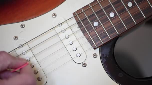 Wideo Zbliżeniem Męskiej Dłoni Zrywającej Struny Gitary Elektrycznej Różowym Plectrum — Wideo stockowe
