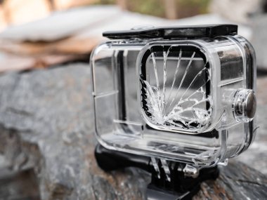 Bir spor kamerasının şeffaf kaplaması hasar görmüş ve lensin zeminine çarpması nedeniyle kullanılamaz durumda. Cam tamamen kırılmış ve bozulmuş.