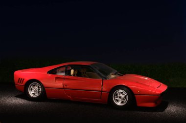 Madrid, İspanya; 05-31-2022: Yandan görülen kırmızı Ferrari GTO arabası, asfalt üzerindeki sokak lambaları ve koyu mavi gece gökyüzü ile aydınlanıyor.