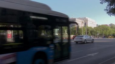 Madrid, İspanya; 06-28-2022: İspanya ve NATO bayrakları ile süslenmiş Madrid 'deki Plaza de Cibeles' ten geçen otobüsler ve çeşitli araçlar, kentte düzenlenen zirve için