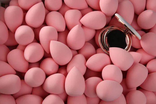 Beauty background a bunch of pink gentle makeup sponges and a mirror — Stock Photo, Image