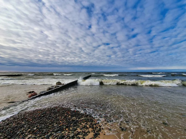 在波罗的海海岸空旷的海滩上 天空戏剧化 乌云密布 海浪在古老的木制防波堤上翻滚 没有人欣赏海滨风景 — 图库照片