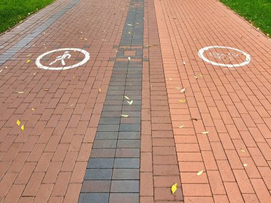 Bisiklet ve yayalar için ayrı şeritleri olan modern güvenli şehir çevresi, kırmızı döşeme kaldırımlarında işaretlerle işaretlenmiş. Kentsel geçmişleri olmayan.