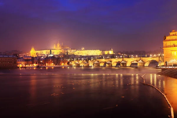 Natt färgglada snöiga gotiska Pragborgen med charles bridge, Tjeckien — Stockfoto