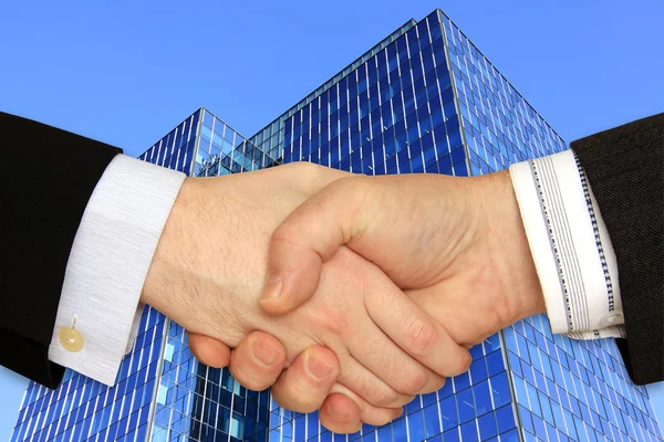 Geschäftsleute geben sich vor dem Wolkenkratzer am blauen Himmel die Hand — Stockfoto