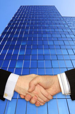 Businessmen shaking hands in front of the modern Building clipart