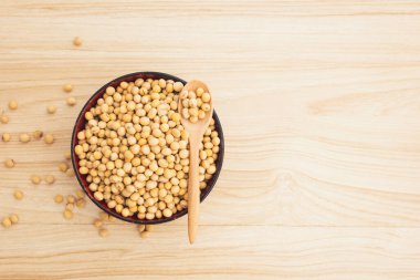 Ahşap zemin üzerinde tahta kaşık olan bir kasede soya fasulyesi, üst görünüm, düz uzanma, tepeden aşağı, seçici odaklanma. Kopyalama alanı.