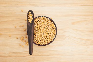 Ahşap zemin üzerinde tahta kaşık olan bir kasede soya fasulyesi, üst görünüm, düz uzanma, tepeden aşağı, seçici odaklanma. Kopyalama alanı.