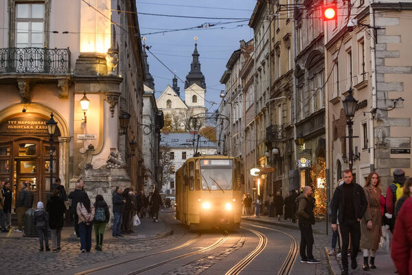 Рынок или Рыночная площадь с традиционным желтым трамваем и кармелитовой церкви на заднем плане. Львов, Украина. Октябрь 2021