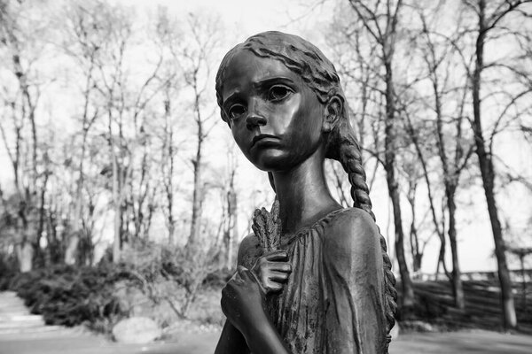 Fragment of Memorial to the victims of the Holodomor, dedicated to victims of the Holodomor (big hunger in Ukraine) 1932 - 1933. Kyiv, Ukraine. November 2021 Girl with spikelets. Black and white photo