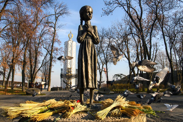 Голуби летают у памятника жертвам Голодомора (большой голод на Украине), которые умерли от голода в 1932-1933 годах. Киев, Украина, октябрь 2021 года. Высокое качество фото
