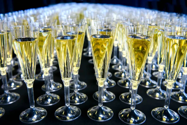 Veel glazen met mousserende wijn of champagne op een donkere achtergrond. Vakantie feeststemming. — Stockfoto