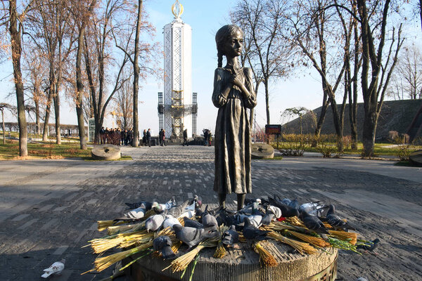 Голуби летают у памятника жертвам Голодомора (большой голод на Украине), которые умерли от голода в 1932-1933 годах. Киев, Украина, октябрь 2021 года. Высокое качество фото