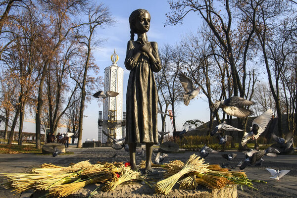 Pigeons fly near the Monument to the victims of the Holodomor (big hunger in Ukraine) who died of starvation in 1932-33. Kyiv, Ukraine, October, 2021. High quality photo