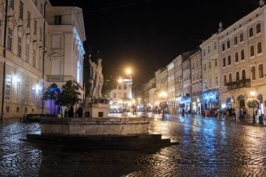 Ukrayna 'nın başkenti Lviv' deki Rynok ya da Market Meydanı 'ndaki çeşmenin üzerindeki Neptune Poseidon heykeline gece yağmurlu manzara. Ekim 2021. Yüksek kalite fotoğraf