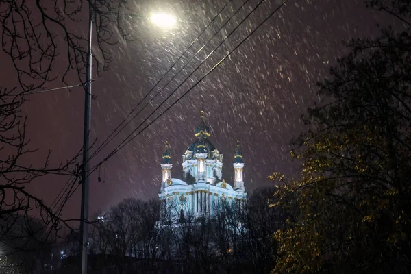 Evening snowy view of St. Andrew Church from Andriyivskyy Uzviz Descent Street in Kyiv, Ukraine. December 2021 — стоковое фото