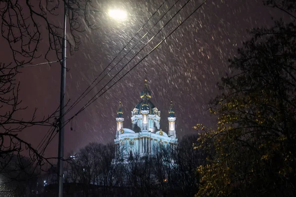 Evening snowy view of St. Andrew Church from Andriyivskyy Uzviz Descent Street in Kyiv, Ukraine. December 2021 — стокове фото